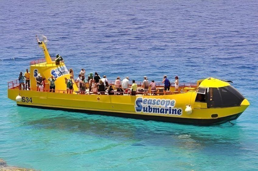 Un submarino amarillo con el texto 'Seascape Submarine' en su costado, identificado con el número 'S34', flotando sobre aguas azul cristalino. 2
