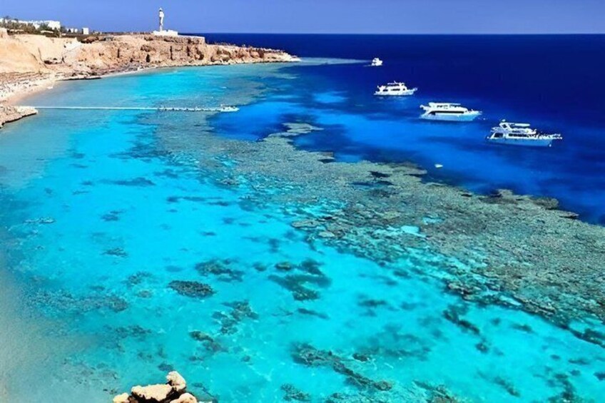 Zona costera con aguas turquesas cristalinas, costas rocosas y varias embarcaciones ancladas cerca de la playa. 4