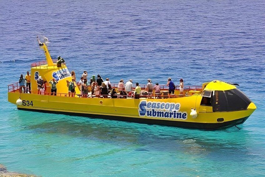 Un sous-marin jaune, portant le nom « Seascape Submarine » sur le côté et l’inscription « S34 », flotte sur une eau d’un bleu limpide. 2
