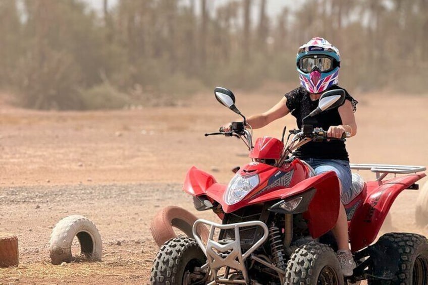 Una persona conduciendo un cuatriciclo rojo por un camino de tierra, con neumáticos y casco. 5