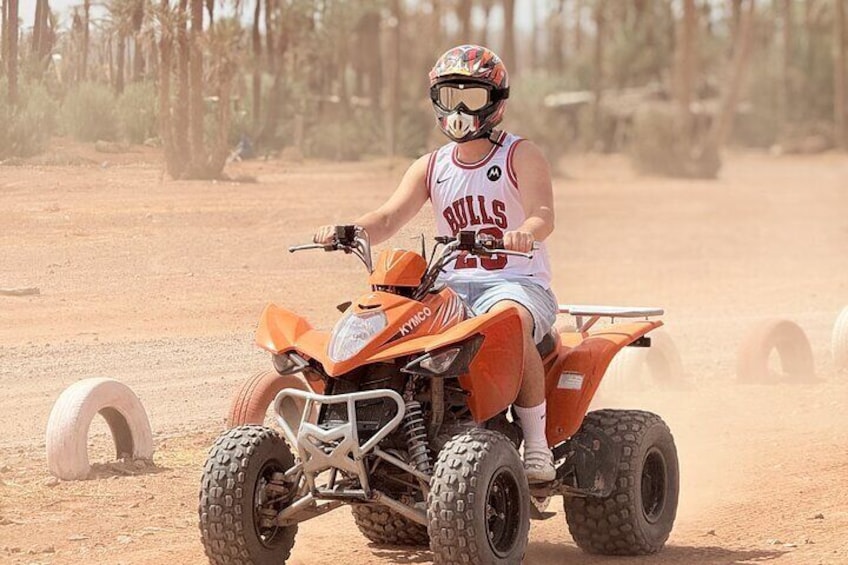 Una persona conduce un cuádruple naranja en un desierto con poca vegetación. 1