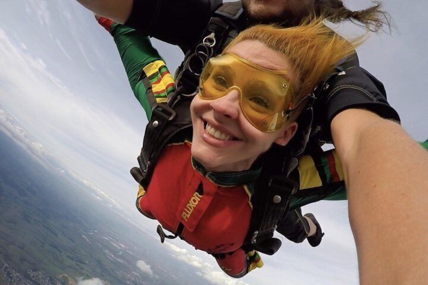 Eine Person mit Fallschirm und einem roten Rucksack mit dem Aufdruck 'JUNIOR' beim Fallschirmspringen. 5