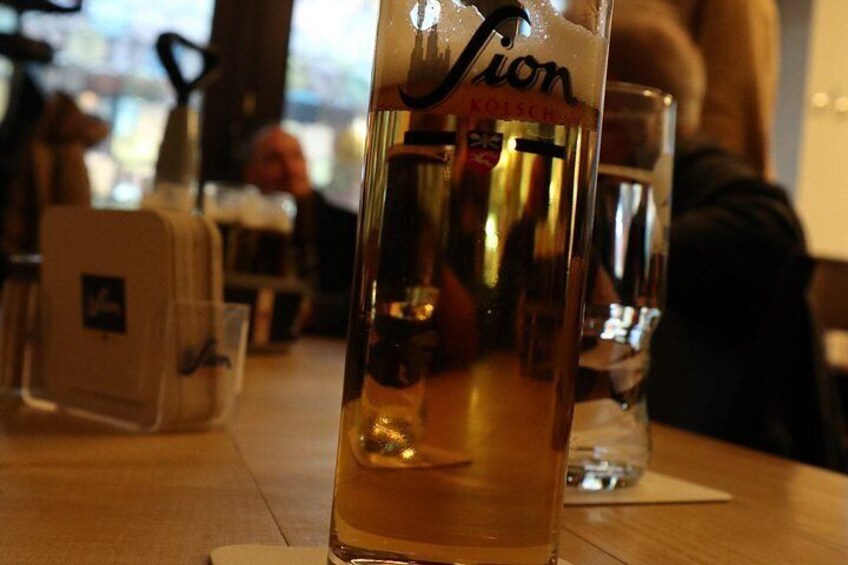 A glass of beer with a label, placed on a wooden table in a restaurant setting. 2