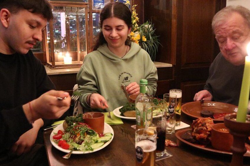 A dining table with plates of food, glasses, and a candle. 5