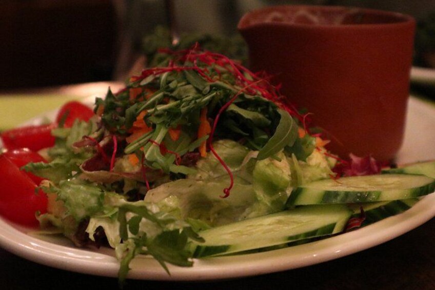 A plate of mixed greens salad with cucumber slices and red bell pepper, accompanied by a red cup. 3