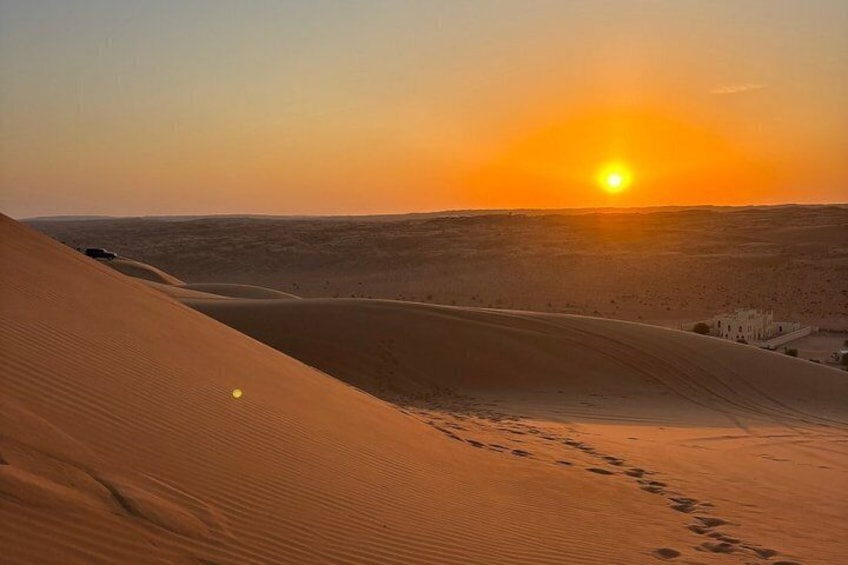A desert landscape with sand dunes and a setting sun. 2