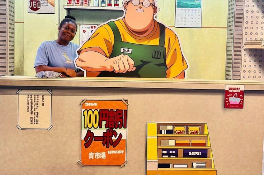 A counter with a person in a yellow shirt and green apron, a woman in a blue shirt, and a sign advertising a 100 yen discount. 5