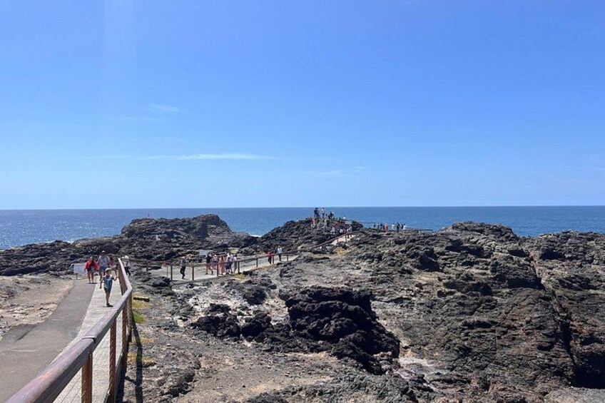 A rocky coastal area with a paved walkway and people walking. 1