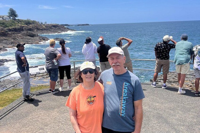 A coastal scene with people standing on a walkway overlooking the ocean. 5