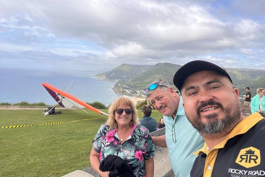 Kystlandskab med en rød hangglider, græsplæne og en person i en gul skjorte. 3