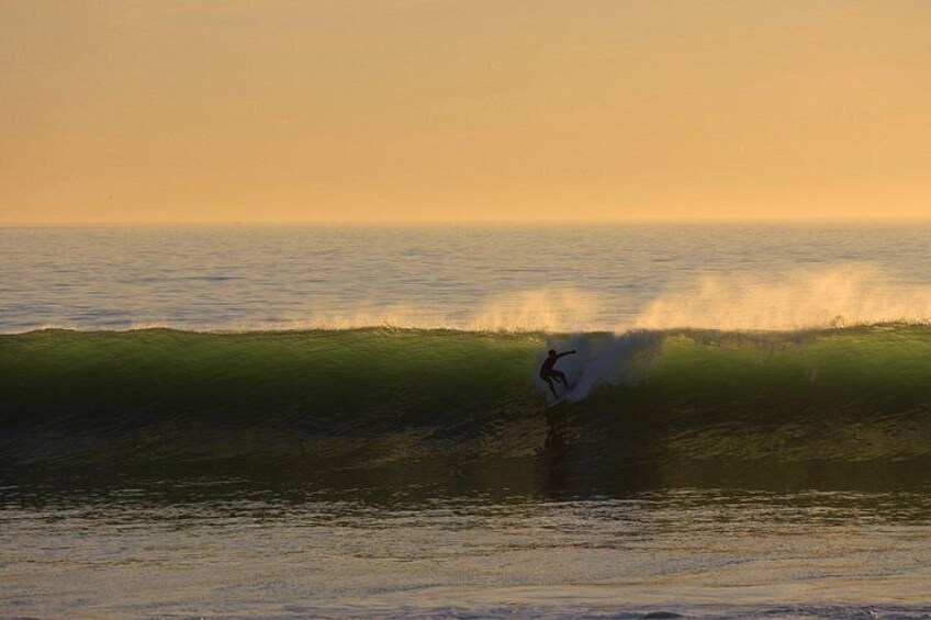Ein Surfer reitet eine Welle bei Sonnenuntergang. 5