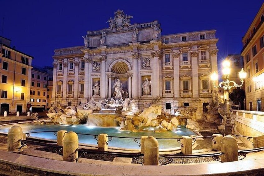 La fontaine de Trevi la nuit, avec ses statues illuminées et ses jets d’eau. 1