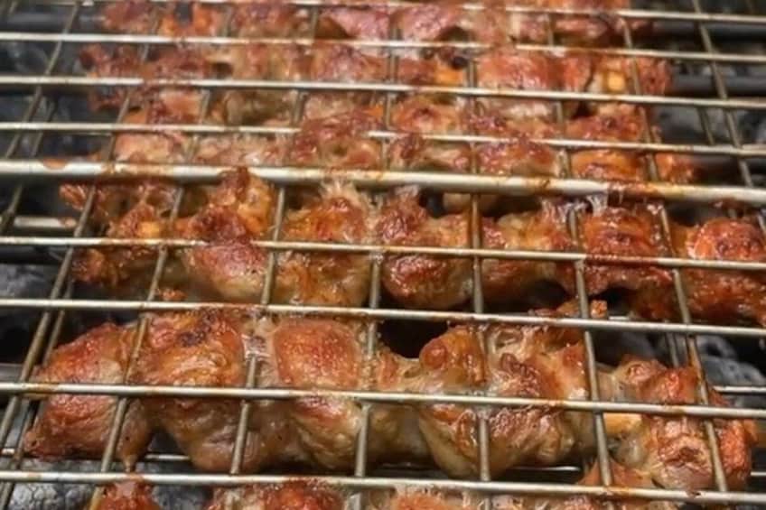 En grill där köttbitar på spett grillas. 2