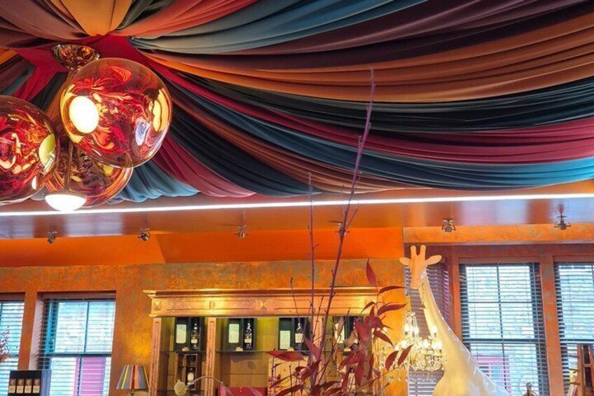 Et værelse med draperet stof, en girafskulptur og en lysekrone. 5