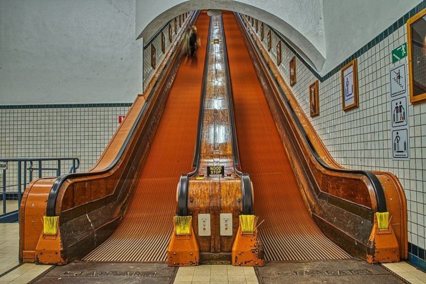A vintage escalator in a subway station with tiled walls and a tiled floor. 2