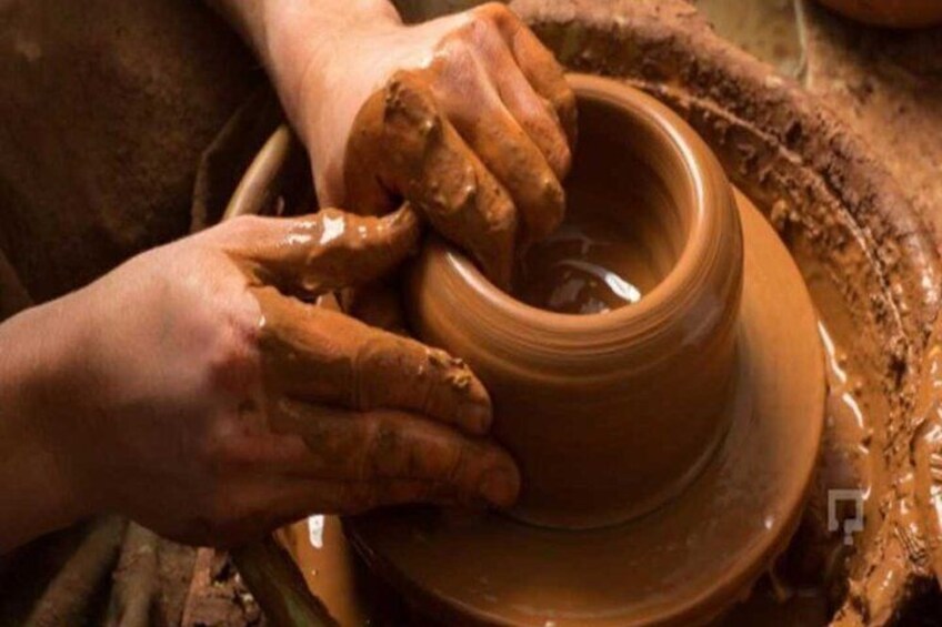 Hands shaping a clay pot on a pottery wheel. 5