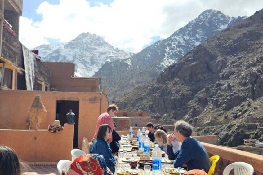 A group of people dining at an outdoor table with a mountainous backdrop. 5