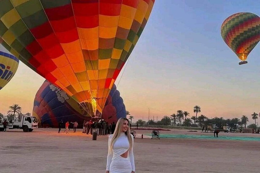 En kvinna som står framför en varmluftsballong med flera olika färger. 3