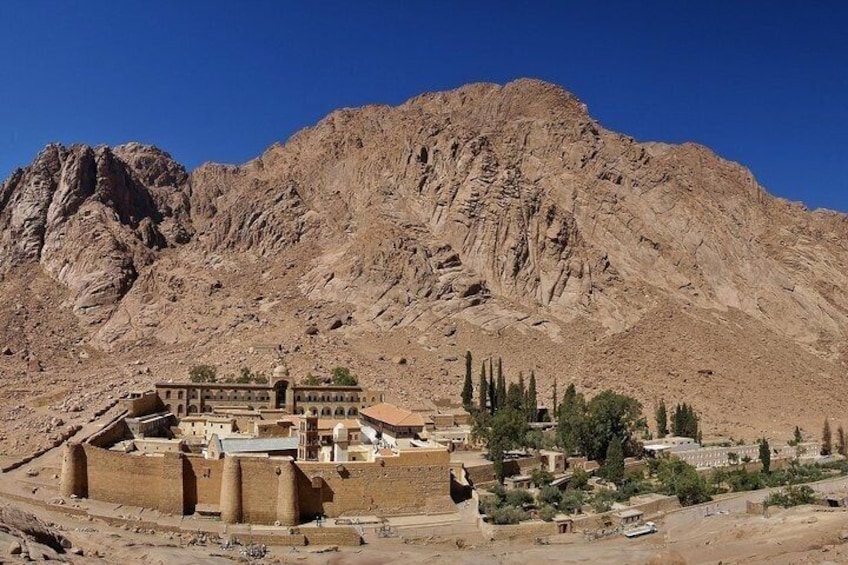 A desert landscape with a large mountain in the background and a historic building complex in the foreground. 5