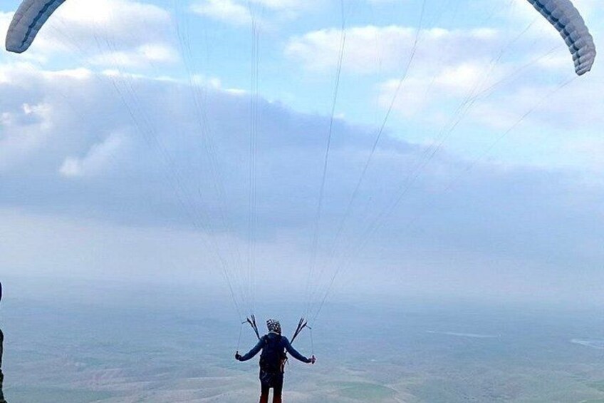 En person paraglider med faldskærm over et stort landskab. 2