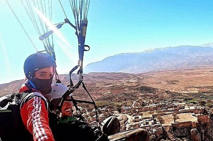 En person paraglider over et bjerglandskab med en landsby nedenfor. 5