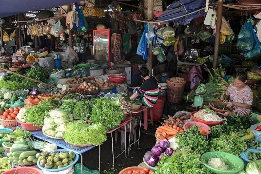 Ein belebter Markt im Freien mit verschiedenen frischen Gemüsesorten und Früchten, die auf Tischen ausliegen. 2