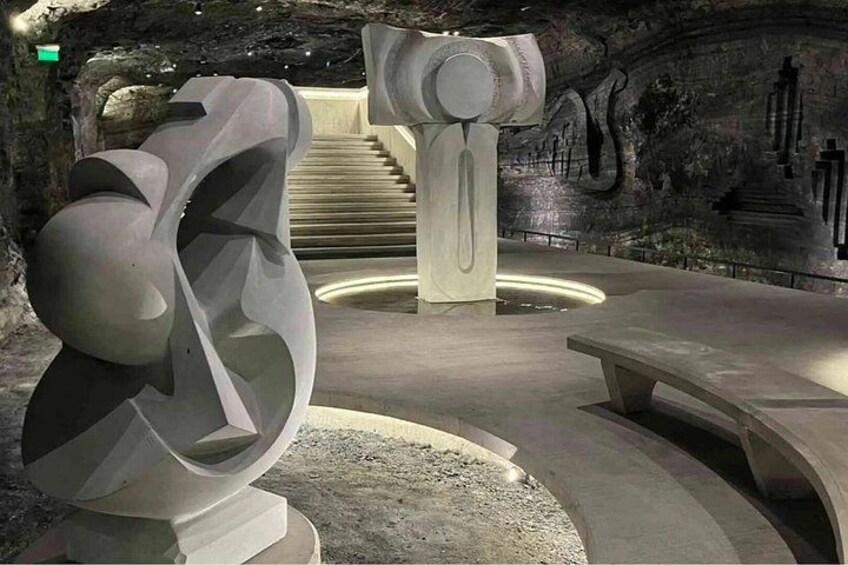 A modern art installation with abstract sculptures and a staircase in a dimly lit room. 2