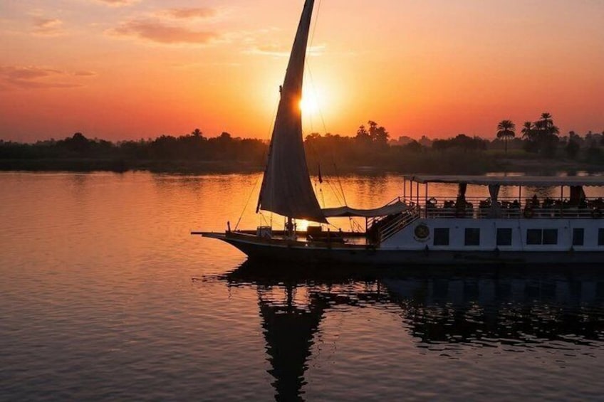A sailboat with a cabin, docked near a sunset over water. 1