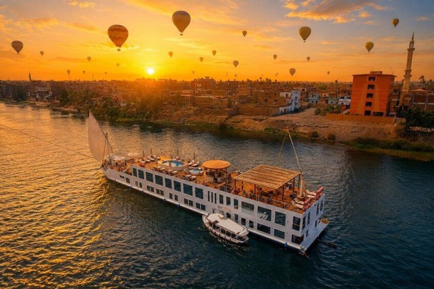 Una nave da fiume con diversi livelli di posti a sedere, uno skyline sullo sfondo e mongolfiere nel cielo. 4