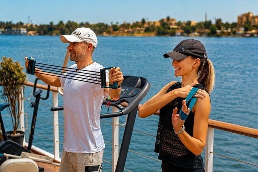 Two people exercising on a treadmill by a waterfront with a cityscape in the background. 4