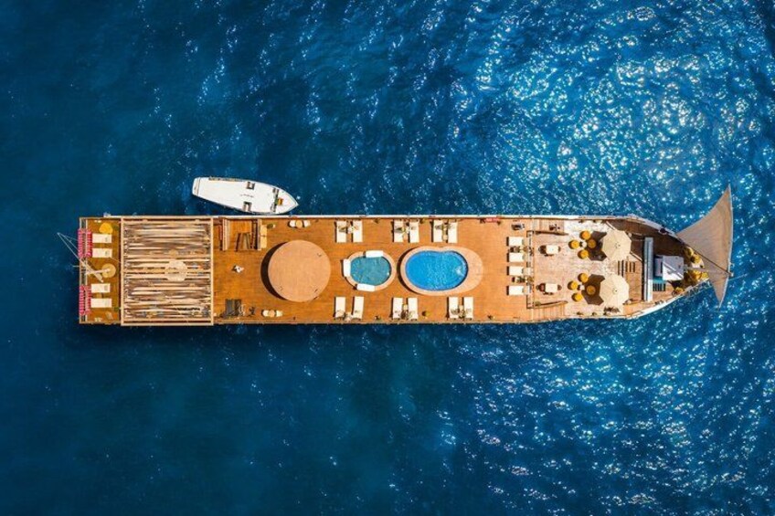 Una nave da crociera con piscina, lettini prendisole e un tender. 5