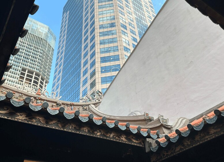 A traditional roof with ornate decorations and a modern skyscraper in the background. 2