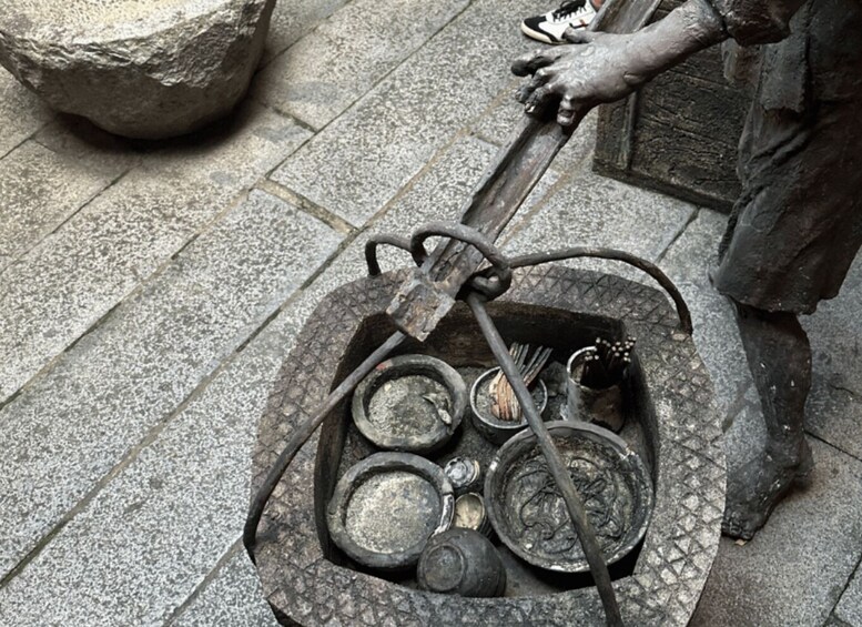 A person cleaning a metal basin with a hose. 3