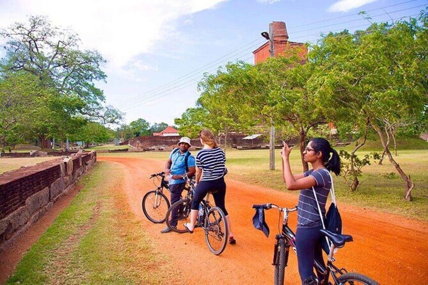 A dirt path with cyclists and a brick building in the background. 4