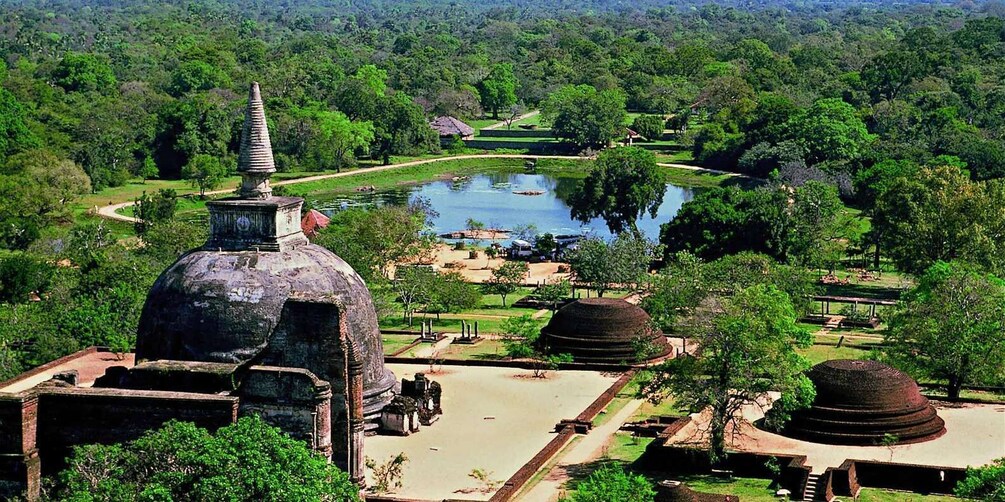 A historical site with a large stupa, a pond, and surrounding greenery. 1