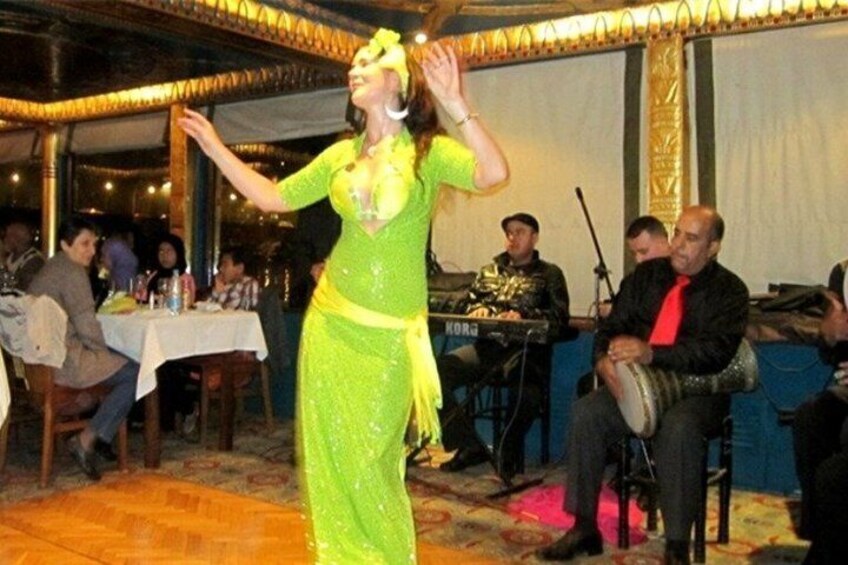 A person in a green dress performing in front of an audience with a band in the background. 4