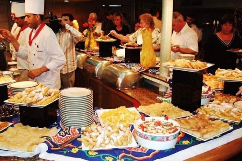 A buffet with various dishes and a chef serving food. 5