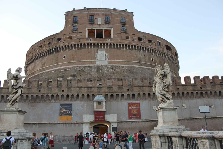 The Colosseum with tourists, statues, and banners. 3