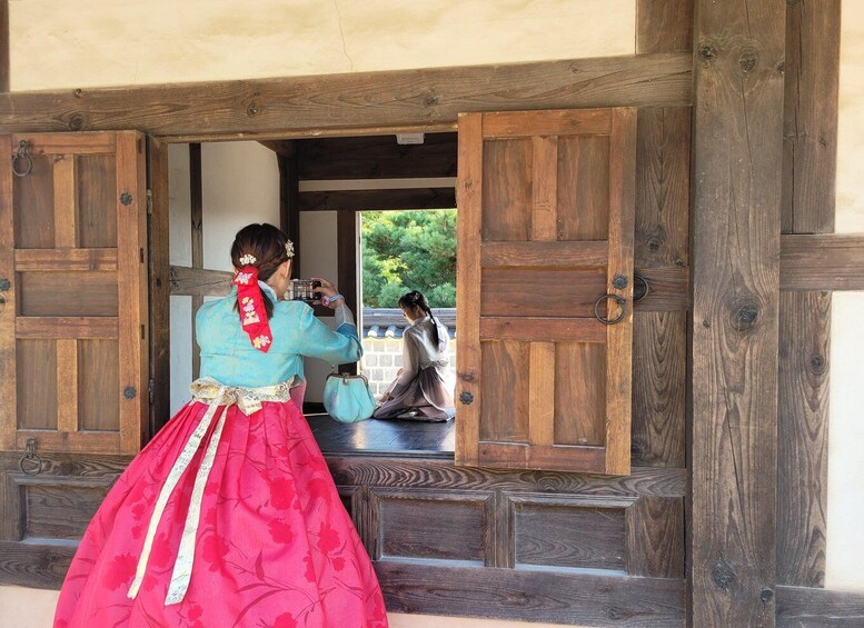 A person in traditional attire taking a photo through a wooden door. 4