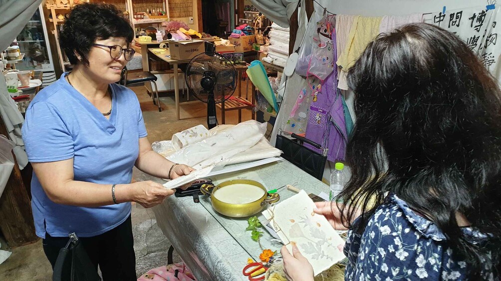 A person cutting paper on a table with a fan and a bowl nearby. 1