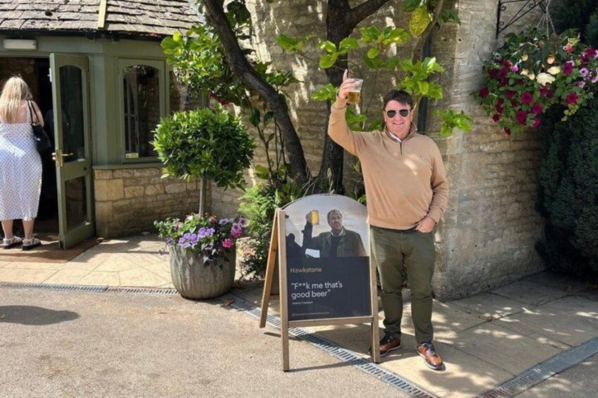 A man holding a beer, a sign with two people, and a building entrance. 3