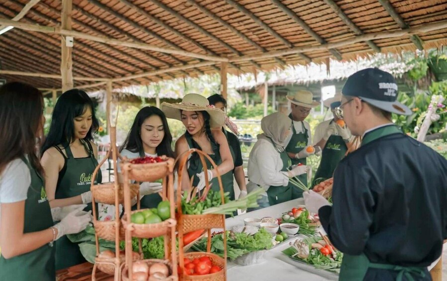 A group of people in aprons preparing food under a thatched roof. 2