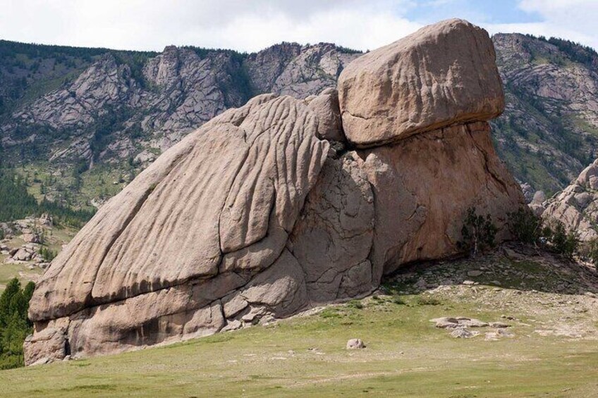 A large rock formation with a prominent overhang in a mountainous landscape. 5
