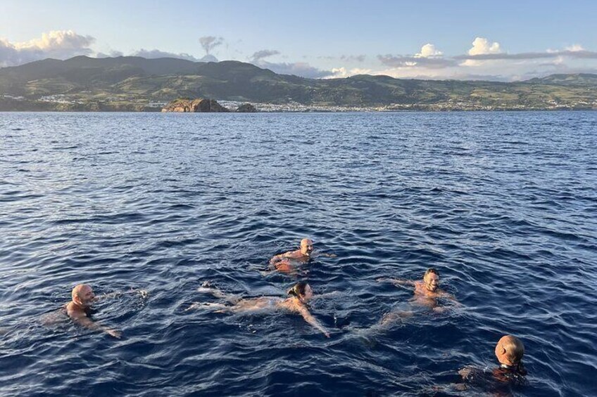 People swimming in a body of water with a mountainous landscape in the background. 5