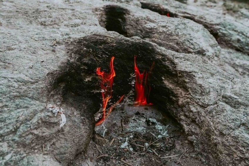 A rock with a small opening emitting red flames. 3