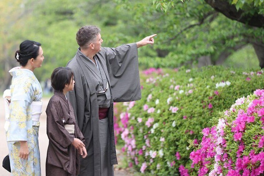 Una persona con vestimenta tradicional señala un árbol, con una niña y una mujer con kimonos cerca. 3