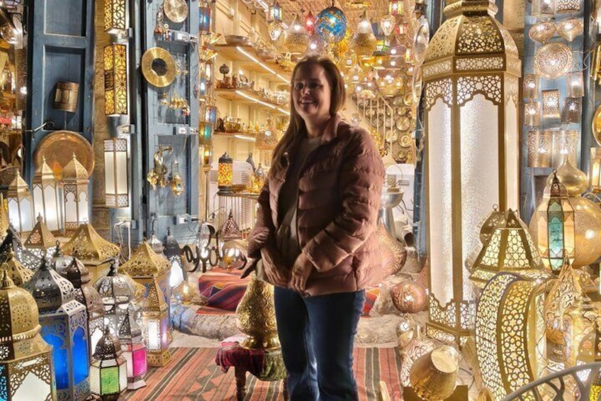 A person standing in a shop filled with ornate lanterns and decorative items. 3