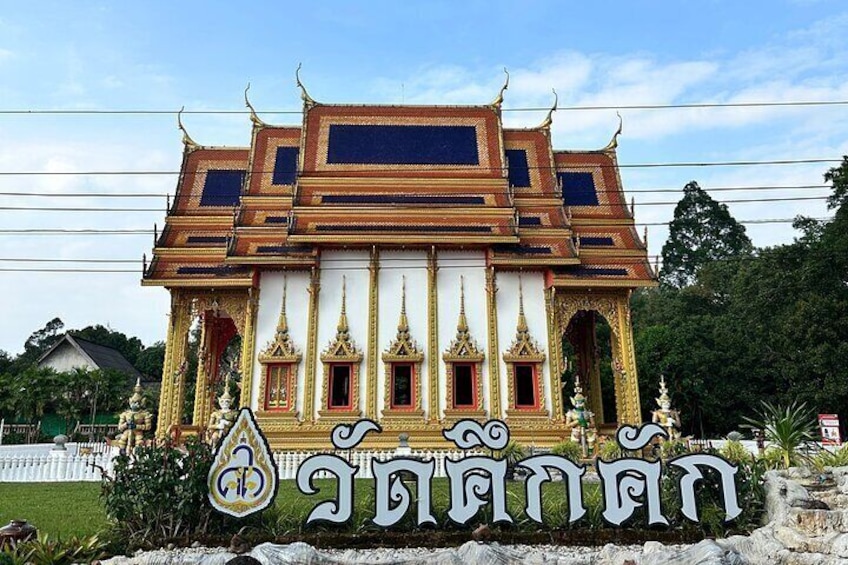 Een traditionele Thaise tempel met versierde architectuur en een bord met Thaise letters. 2