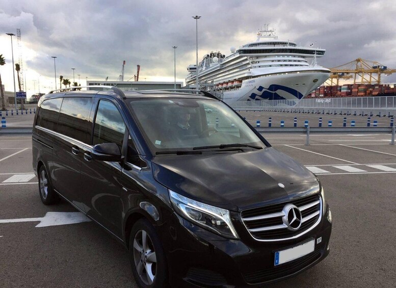 Musta Mercedes-Benz-merkkinen maasturi on pysäköity satama-alueelle, ja taustalla näkyy risteilyalus. 2