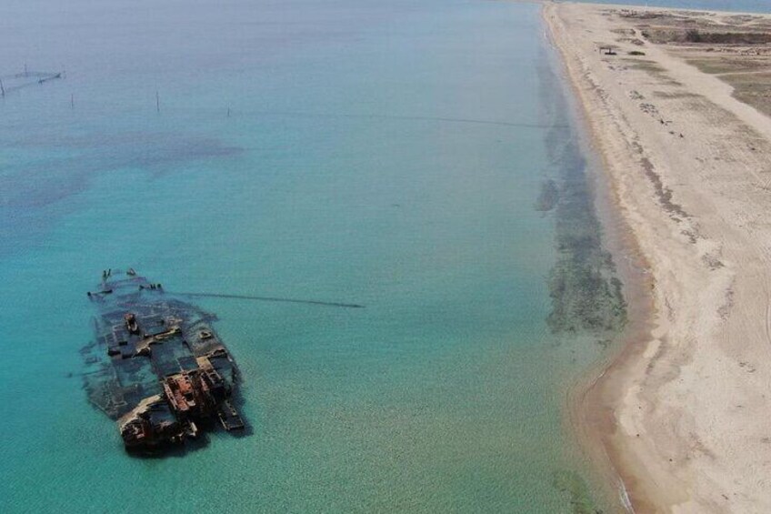 Een gezonken schip in helder turquoise water nabij een zandstrand. 1